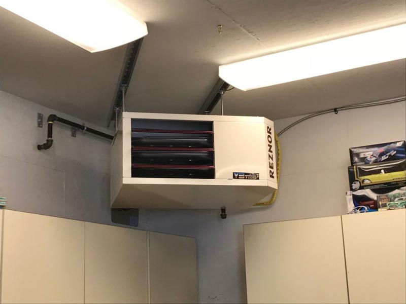 A wall-mounted refrigerator and ceiling heater in a garage setting in Edmonton, AB.