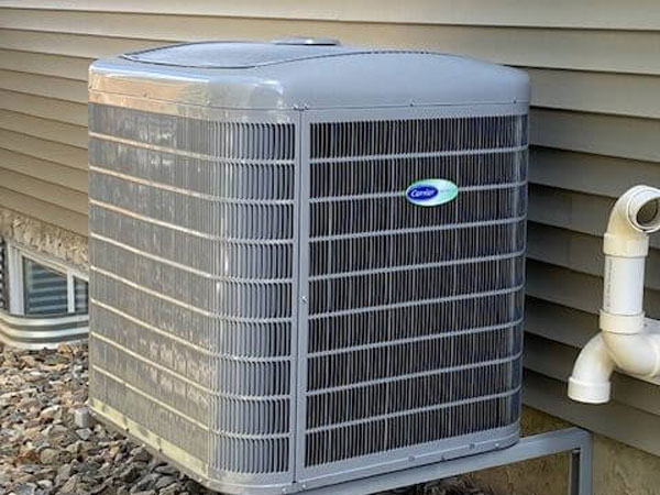 A Carrier AC unit mounted on the side of a house in Edmonton, AB