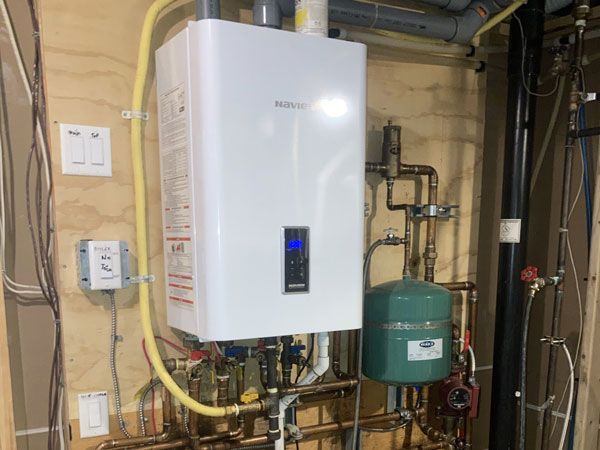A gas water heater installed in a room with visible pipes, located in Edmonton, AB