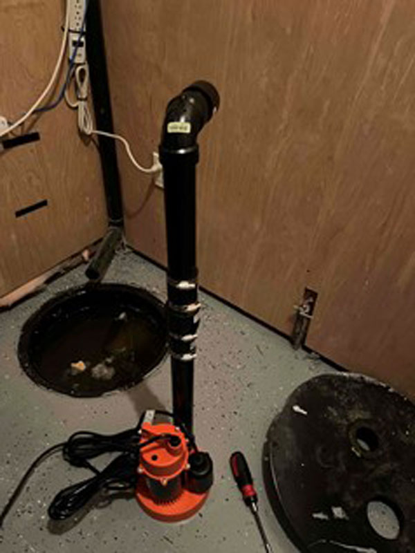 A black and orange sump pump positioned on the floor in Edmonton, AB