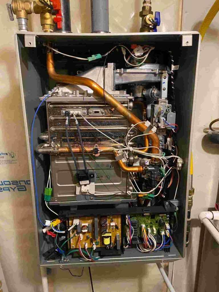 Internal view of a gas furnace with wires and pipes, situated in Edmonton, AB