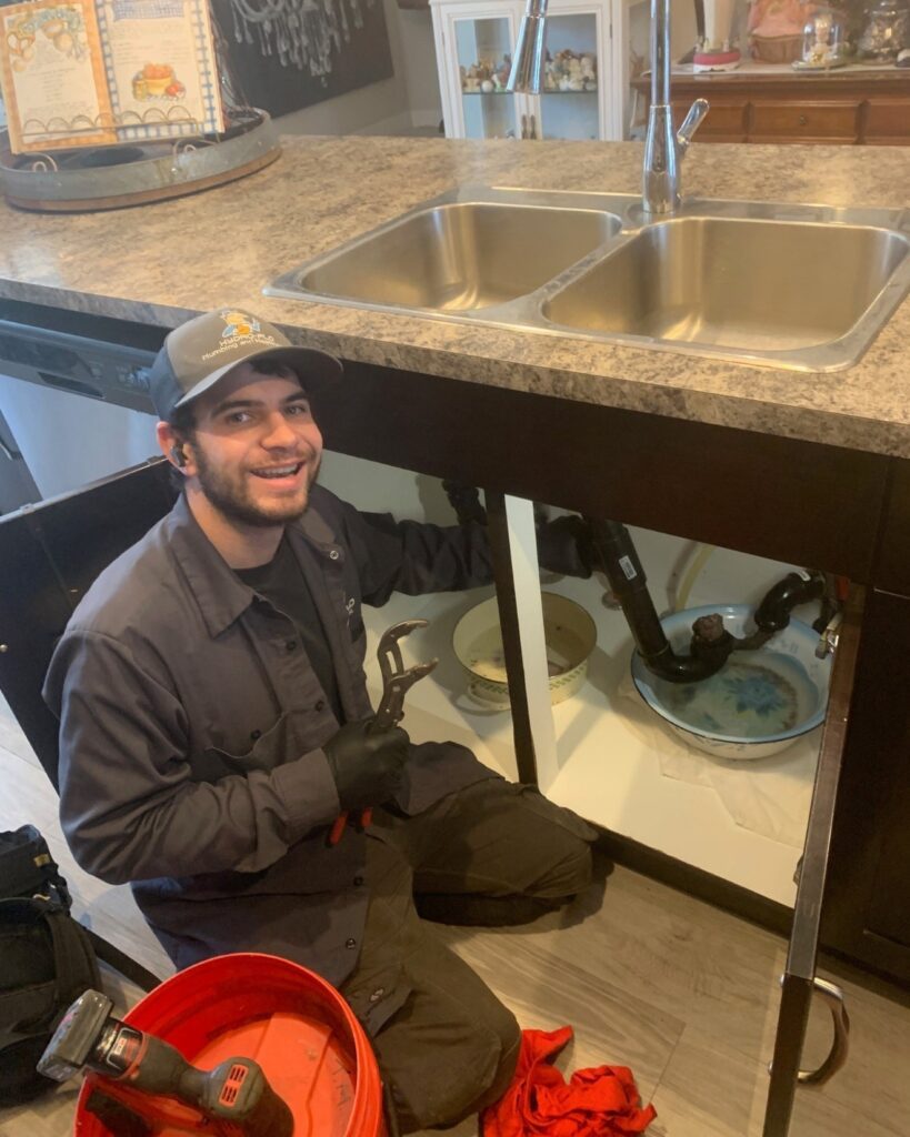 A Hydro-Flo Plumbing & Heating drain cleaning tech unclogging a kitchen sink