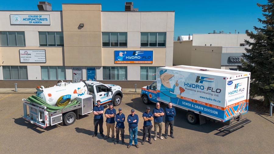 Hydro-Flo plumbing team standing between two branded service trucks