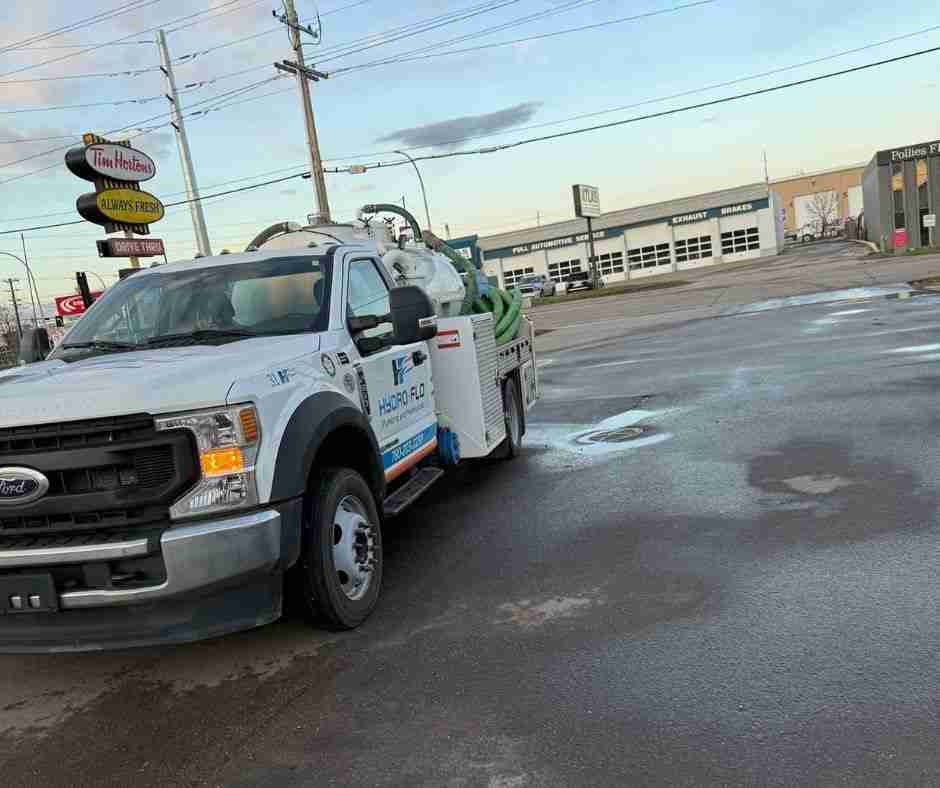 A white Hydro-Flo Plumbing & Heating truck parked at a gas station in Edmonton, AB